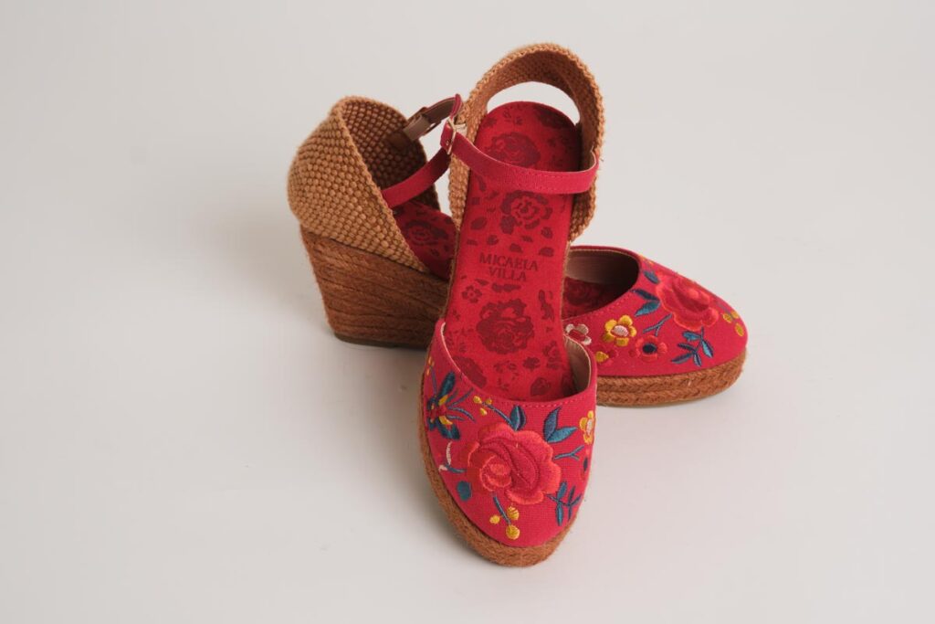 Alpargatas de cuña en vibrante color rojo, realzadas por un colorido bordado floral con rosas en la puntera. Diseñadas con pulsera ajustable y acabado en esparto, combinan la tradición flamenca con un estilo alegre, ofreciendo gran comodidad para tus conjuntos de moda flamenca.