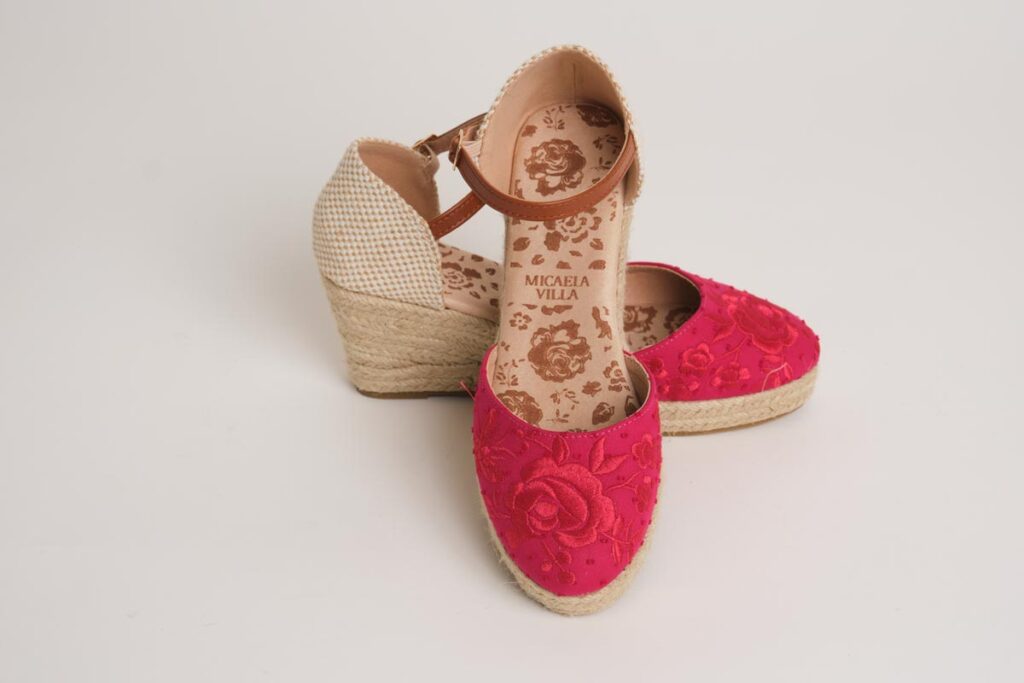 Alpargatas de cuña en un intenso color fucsia, decoradas con un elegante bordado floral en la puntera. Diseño con pulsera ajustable y acabado en esparto, ideales para añadir un toque de vivacidad, elegancia y comodidad a cualquier look de flamenca.