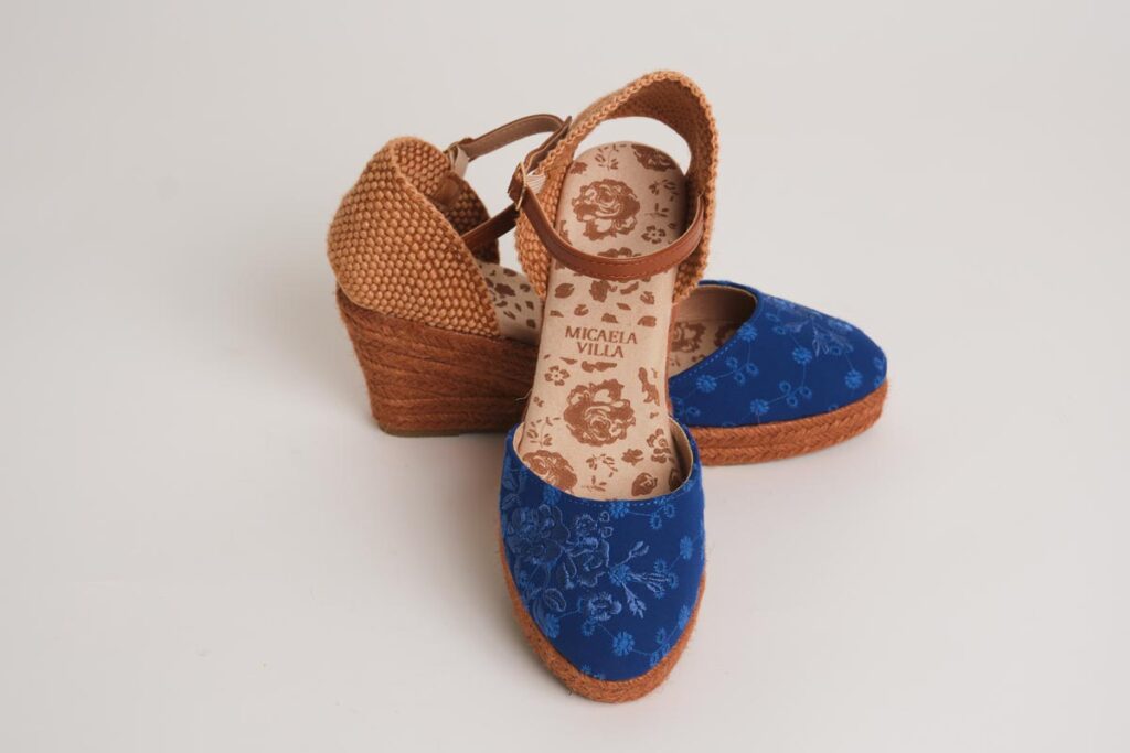 Sofisticadas alpargatas de cuña en un vibrante tono azul, realzadas con delicados bordados florales en la puntera. Diseño con cierre de pulsera ajustable y acabado en esparto, ideales para añadir un toque de distinción, elegancia y comodidad a tus conjuntos de flamenca.