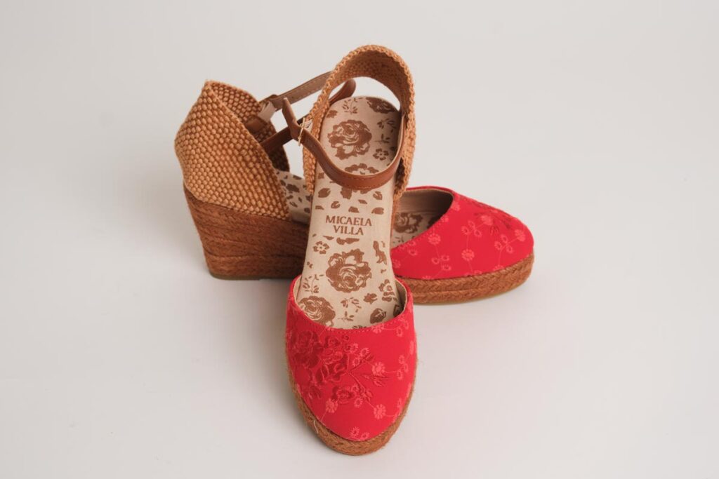 Sofisticadas alpargatas de cuña en un apasionado tono rojo, decoradas con sutiles bordados florales en la puntera. Diseño con cierre de pulsera ajustable y acabado en esparto, la opción perfecta para añadir un toque de color, elegancia y comodidad a tus estilismos de flamenca.