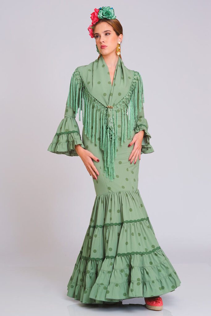 Descubre este sofisticado vestido de flamenca en tono verde oliva con sutiles lunares a tono. Su corte sirena entallado define la silueta con elegancia, mientras que la falda estructurada en volantes proporciona un movimiento dinámico y auténtico para cualquier evento.