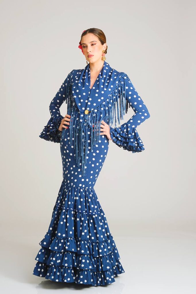 Vestido de flamenca en un profundo tono azul con estampado de lunares blancos, diseñado con una silueta entallada tipo sirena y una falda rematada en volantes que aporta elegancia y movimiento a la prenda.