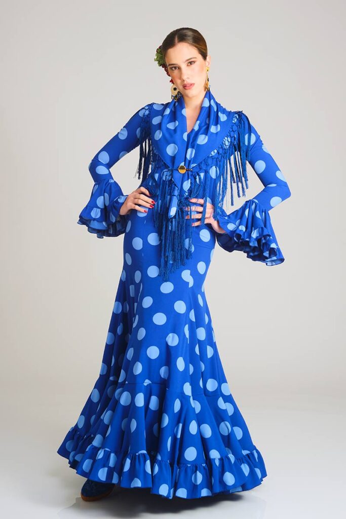 Vestido de flamenca con estampado de lunares en dos tonos de azul, destacando por su silueta entallada tipo sirena y una falda estructurada con volantes que aporta elegancia y movimiento al conjunto.