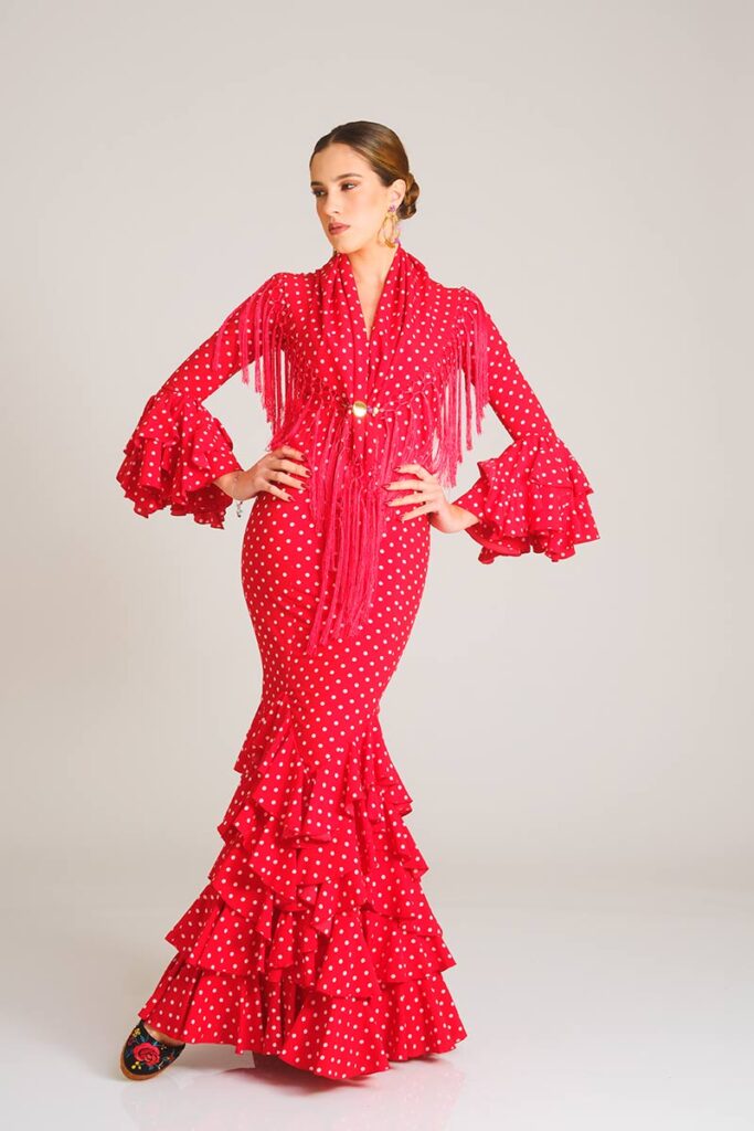 Vestido de flamenca con diseño clásico en rojo vibrante estampado con lunares blancos, caracterizado por su ajuste entallado y falda con volantes múltiples, ofreciendo una estética tradicional y favorecedora.