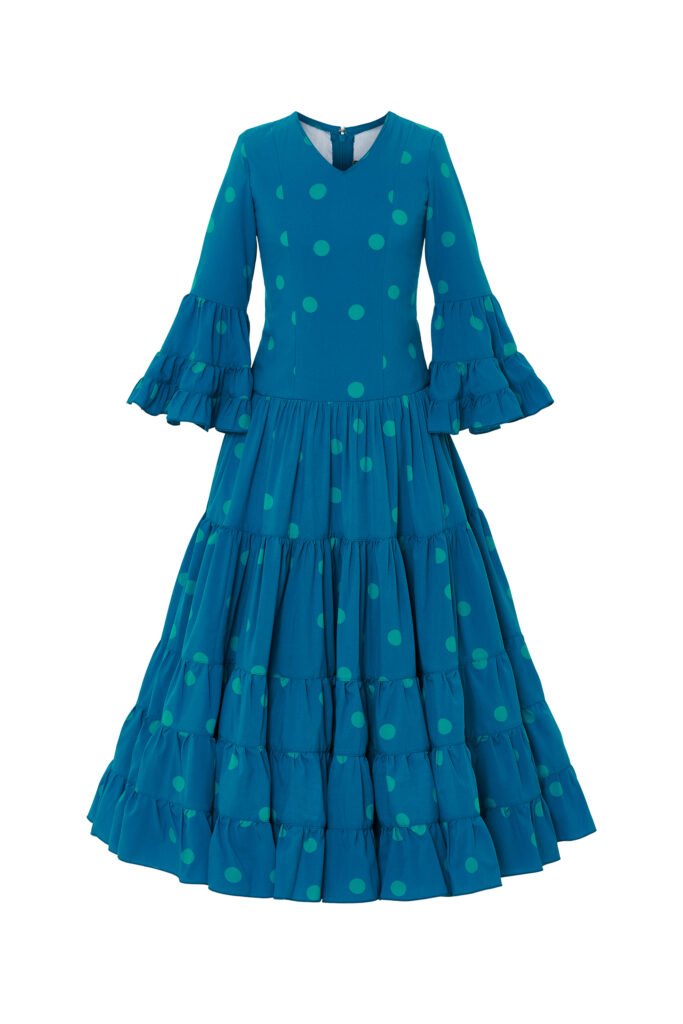 Alegre traje de flamenca infantil en color azul petróleo con estampado de lunares, diseñado con cuerpo entallado y falda de volantes escalonados que aportan gran movimiento, una opción perfecta para lucir un estilo tradicional y festivo en cualquier feria o evento andaluz