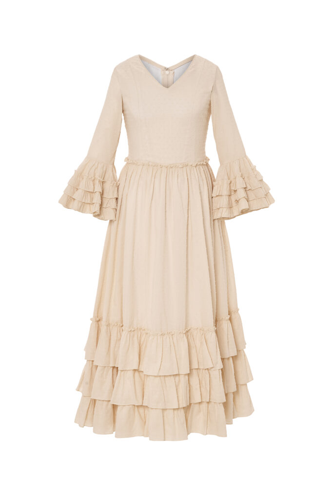 Elegante y sencillo traje de flamenca infantil en color beige, diseñado con un corte clásico que incorpora volantes en mangas y falda, ofreciendo un estilo tradicional y refinado ideal para cualquier evento o feria andaluza