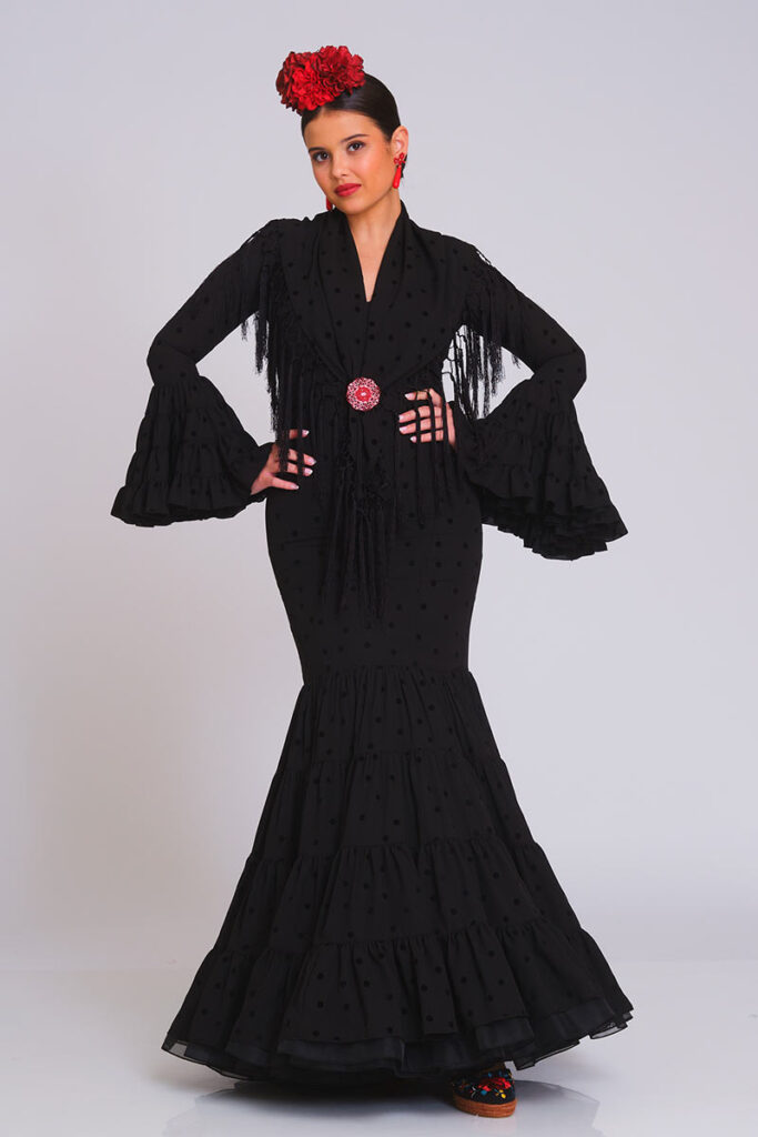 Sofisticado traje de flamenca en color negro con un sutil patrón de lunares, que destaca por su corte ajustado y la elegante caída de sus volantes en falda y mangas
