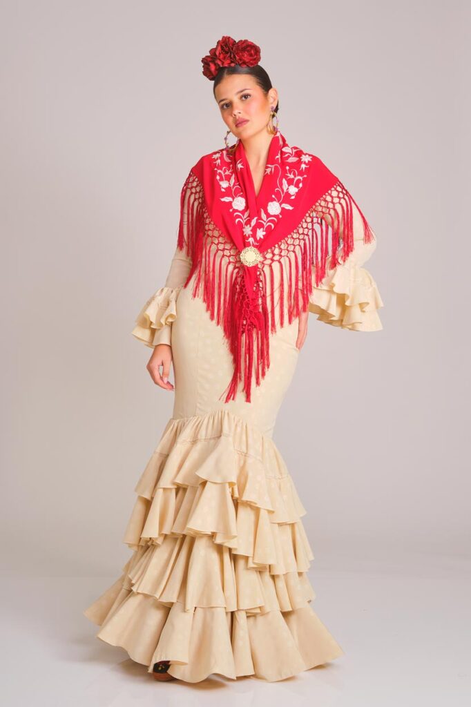 Traje de flamenca beige con estampado sutil de lunares, diseño entallado con volantes en falda y mangas, ideal para ferias y eventos andaluces