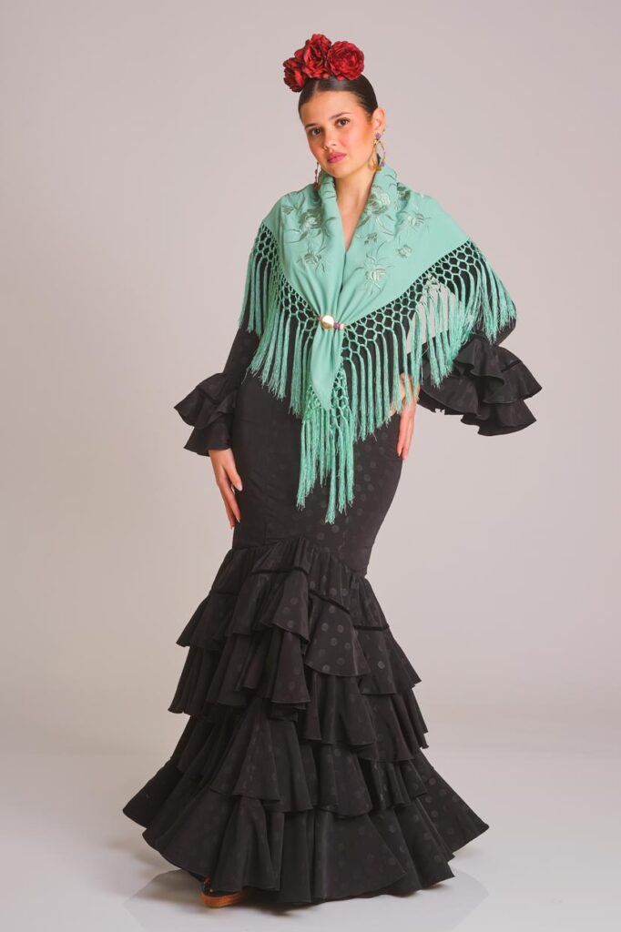 Traje de flamenca negro con lunares tonales, diseño entallado con volantes en falda y mangas, ideal para eventos y ferias