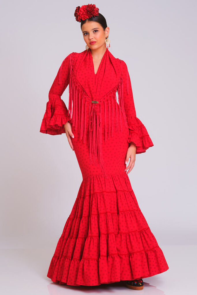 Traje de flamenca rojo con estampado sutil de lunares, diseño entallado con volantes en la falda y mangas, incluye mantoncillo con flecos a juego