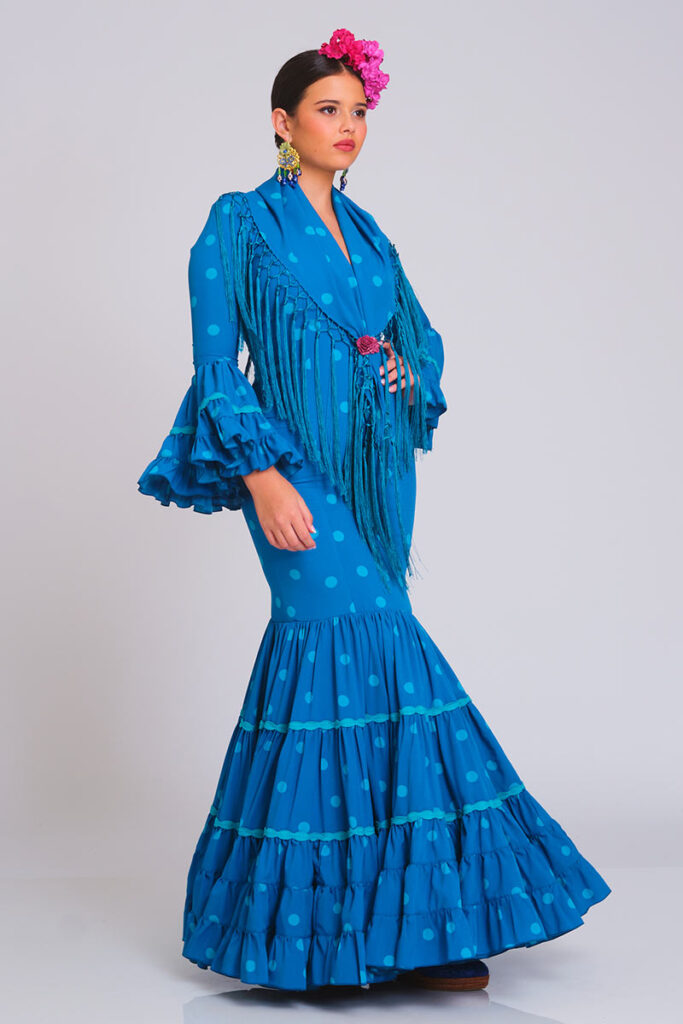 Traje de flamenca azul vibrante con lunares, diseño entallado con volantes en la falda y mangas, incluye mantoncillo con flecos a juego