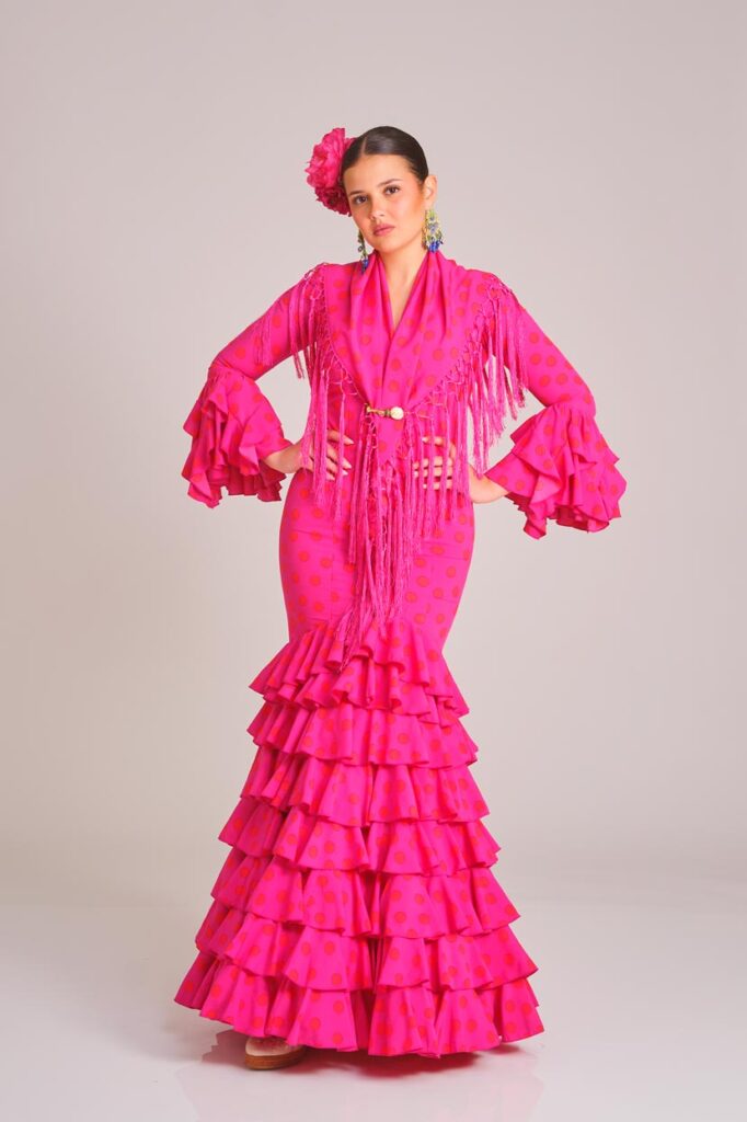 Traje de flamenca fucsia con lunares, diseño de volantes en cascada y mantoncillo a juego, perfecto para la Feria de Abril