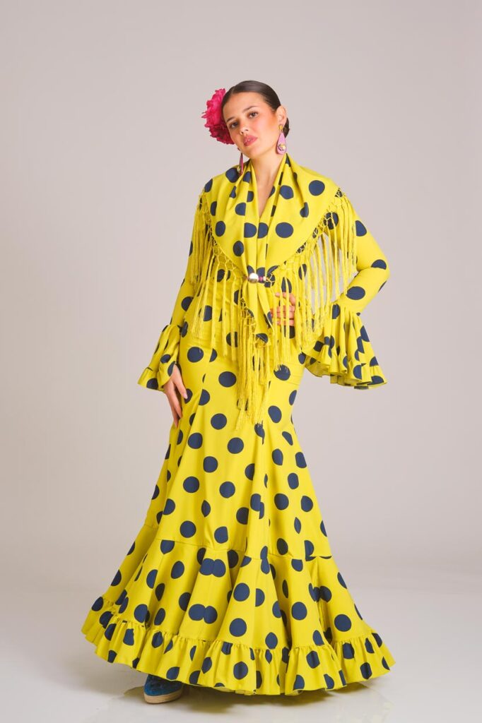 Traje de flamenca largo verde manzana con lunares azules elegante, con falda de flecos y mangas abullonadas, un diseño clásico y vibrante para la feria