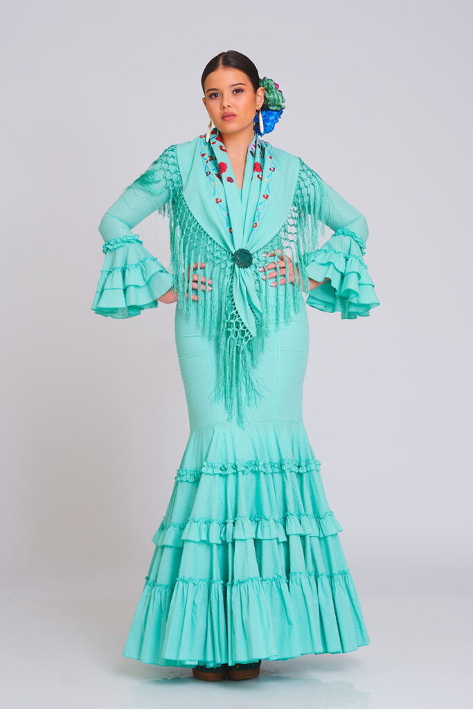 Vestido de flamenca verde menta de corte sirena con mantoncillo bordado, flecos largos y mangas con volantes