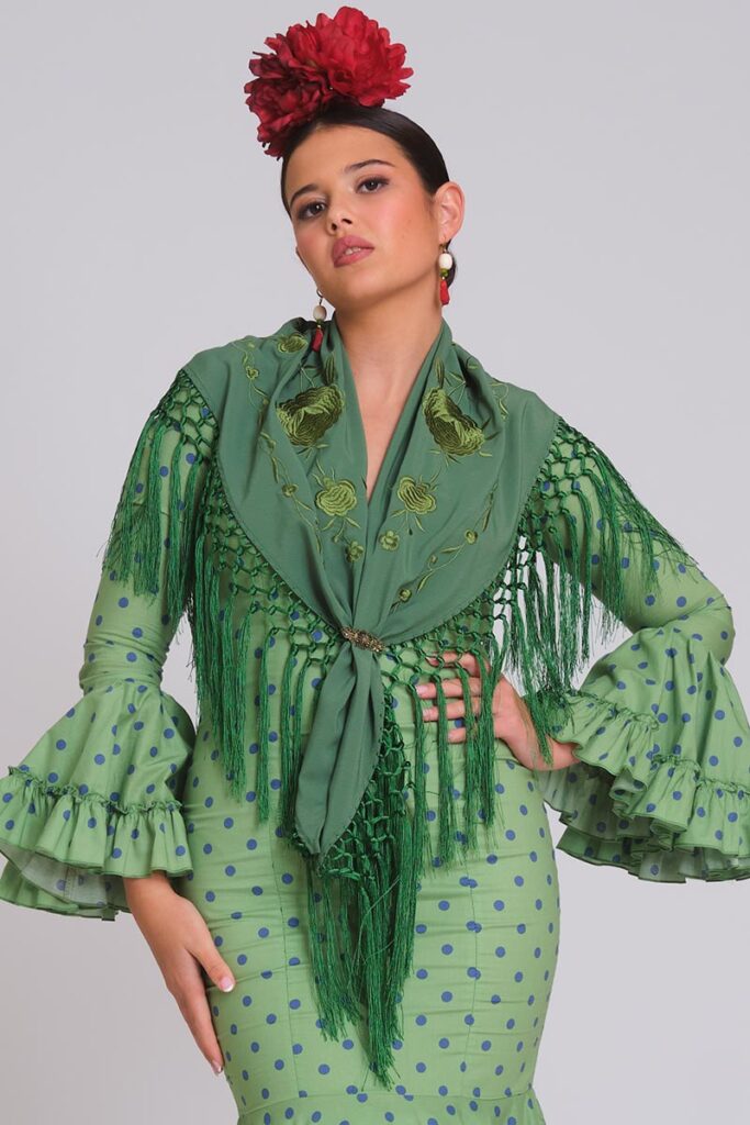 Traje de flamenca verde con lunares azules, mantoncillo bordado tono sobre tono, flecos largos y mangas de volantes