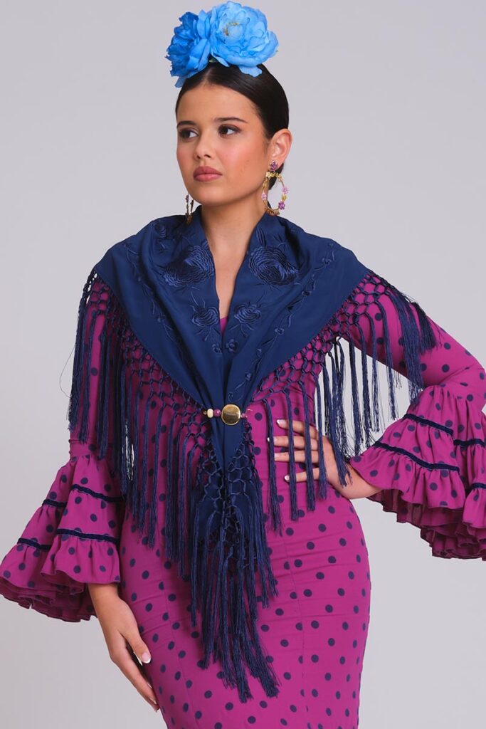 Vestido de flamenca fucsia de lunares con mantoncillo azul marino bordado, flecos largos y mangas de volantes