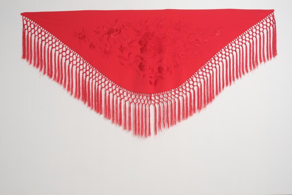 Mantón rojo de moda flamenca con bordado floral tono sobre tono y flecos largos de macramé