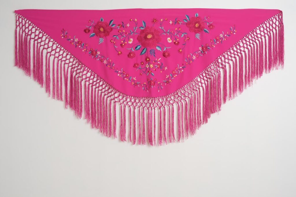 Mantón fucsia de moda flamenca con rosas bordadas, hojas turquesa y flecos largos de macramé