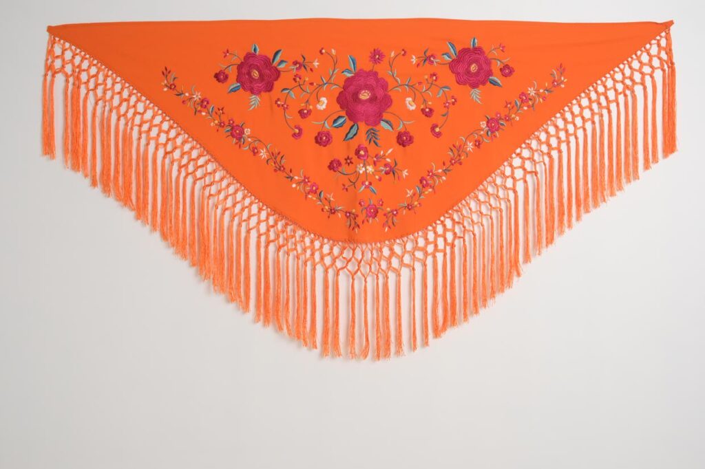 Mantón flamenco naranja con bordado de rosas fucsias, motivos vegetales y flecos largos de macramé