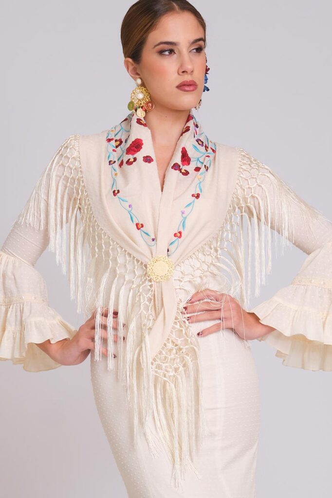 Estilismo de moda flamenca en marfil con mantoncillo bordado de rosas, flecos artesanales y mangas con volantes