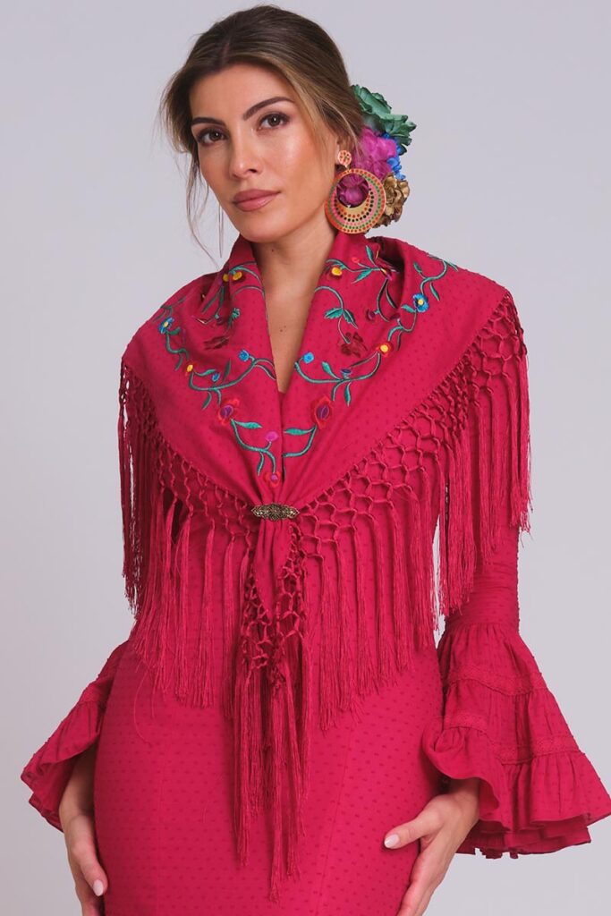 Look de moda flamenca cereza con mantoncillo floral bordado, flecos largos y mangas con volantes