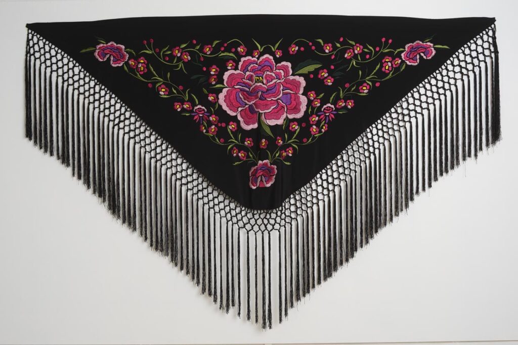 Mantón negro de moda flamenca con bordado de peonías rosas y flecos largos anudados