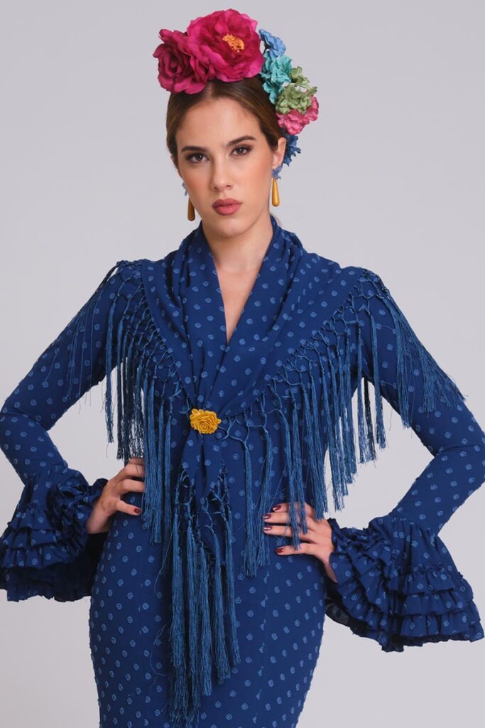 Vestido de flamenca azul tinta de plumeti con relieve, mangas de volantes múltiples y mantoncillo de flecos largos azul azafata.
