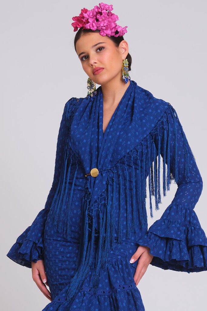 Vestido de flamenca azul cobalto de tejido perforado calado, mangas de volantes múltiples y mantoncillo de flecos largos a juego.