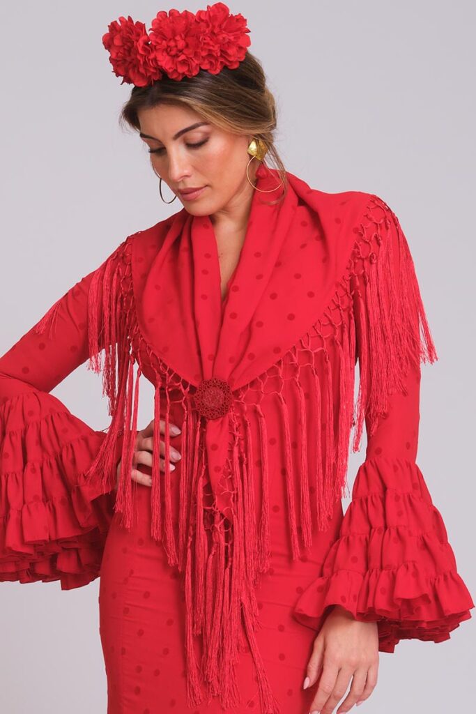 Vestido de flamenca rojo con lunares medianos al tono, mangas con volantes triples y mantoncillo de flecos largos rojo pasión.