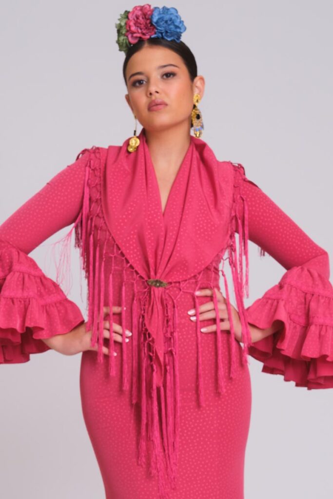 Vestido de flamenca buganvilla con micropatrón de lunares al tono, mangas con volantes dobles y mantoncillo de flecos largos.