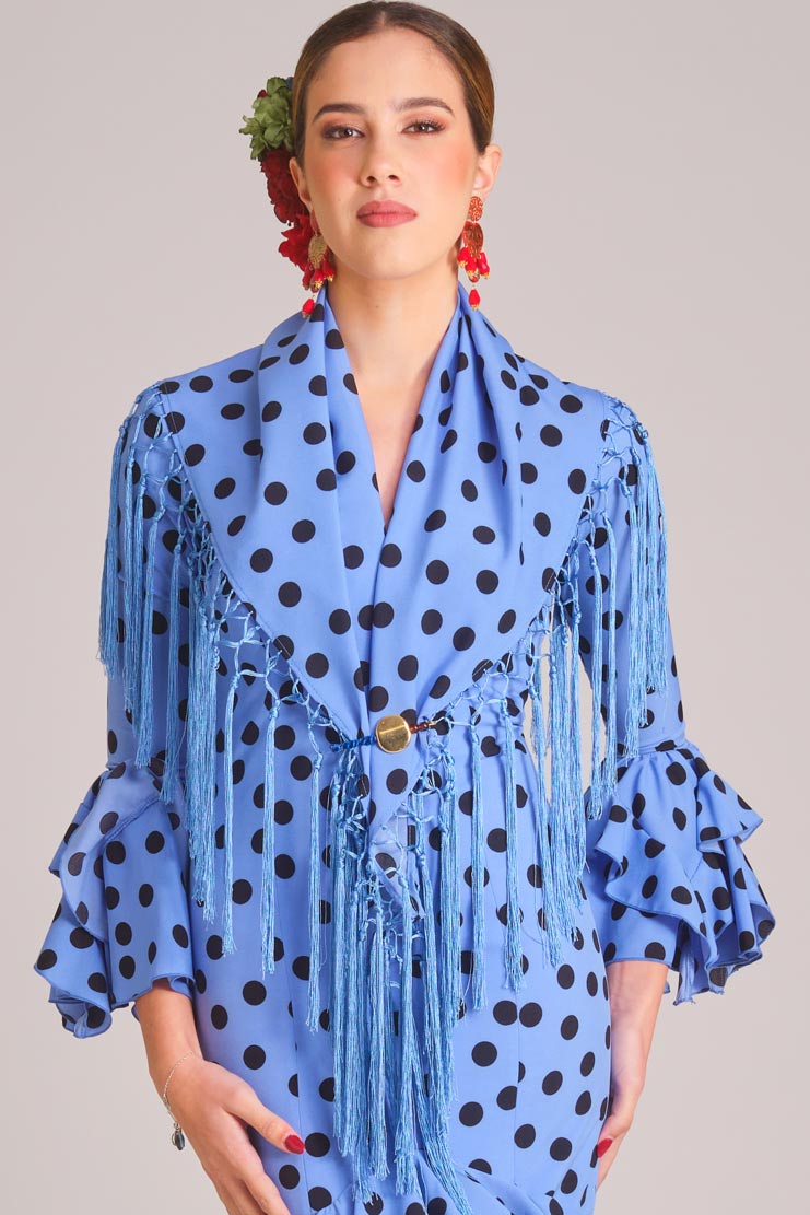 Traje de flamenca azul claro con lunares negros, mantoncillo de flecos y volantes para feria