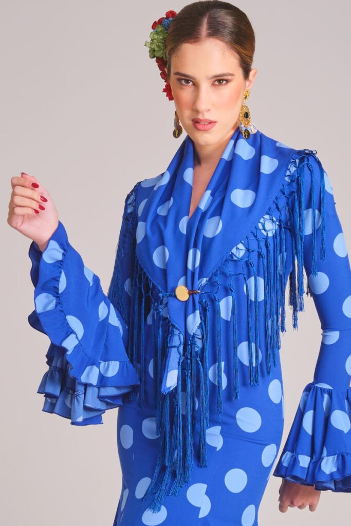 Traje de flamenca azul con lunares celestes, mantoncillo de flecos y mangas con volantes para feria
