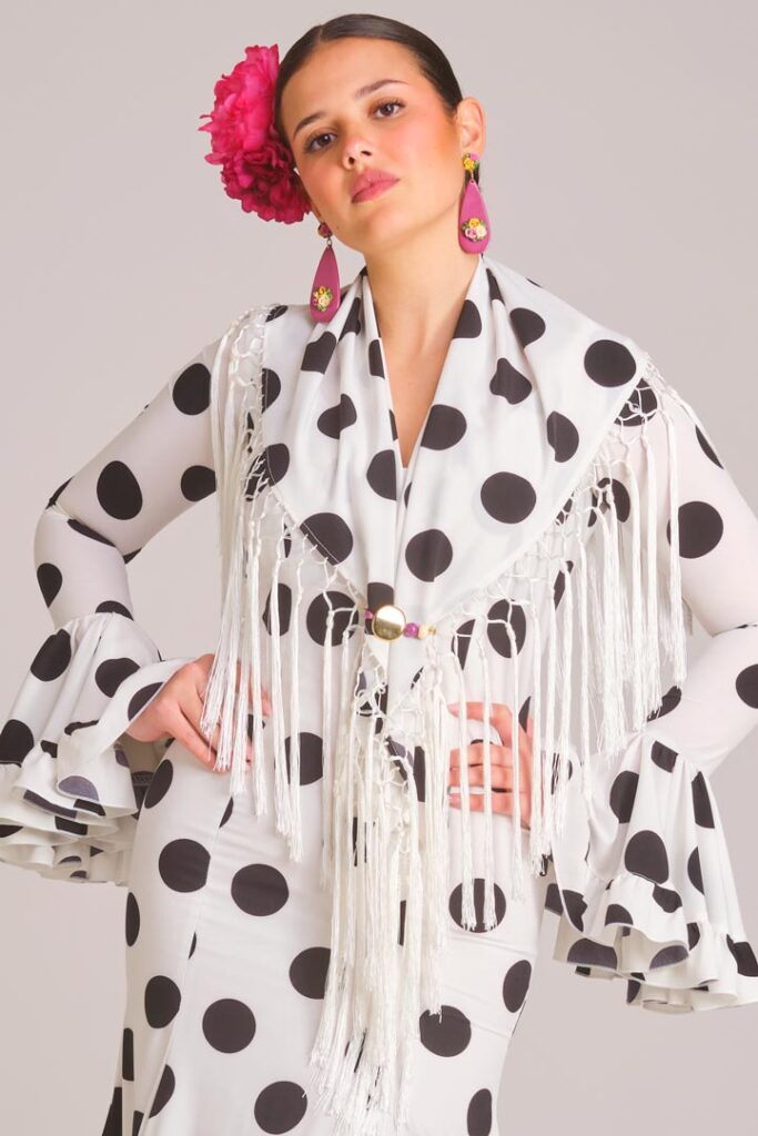 Traje de flamenca blanco con lunares negros, mantoncillo a juego y flecos para Feria de Abril