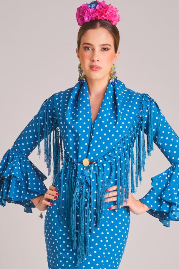 Traje de flamenca azul con lunares blancos, mantoncillo a juego y flecos para feria