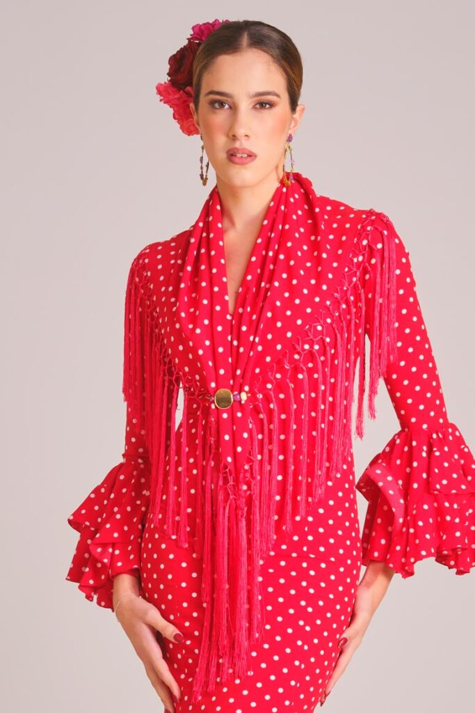Traje de flamenca rojo con lunares blancos, mantoncillo a juego y flecos para Feria de Abril