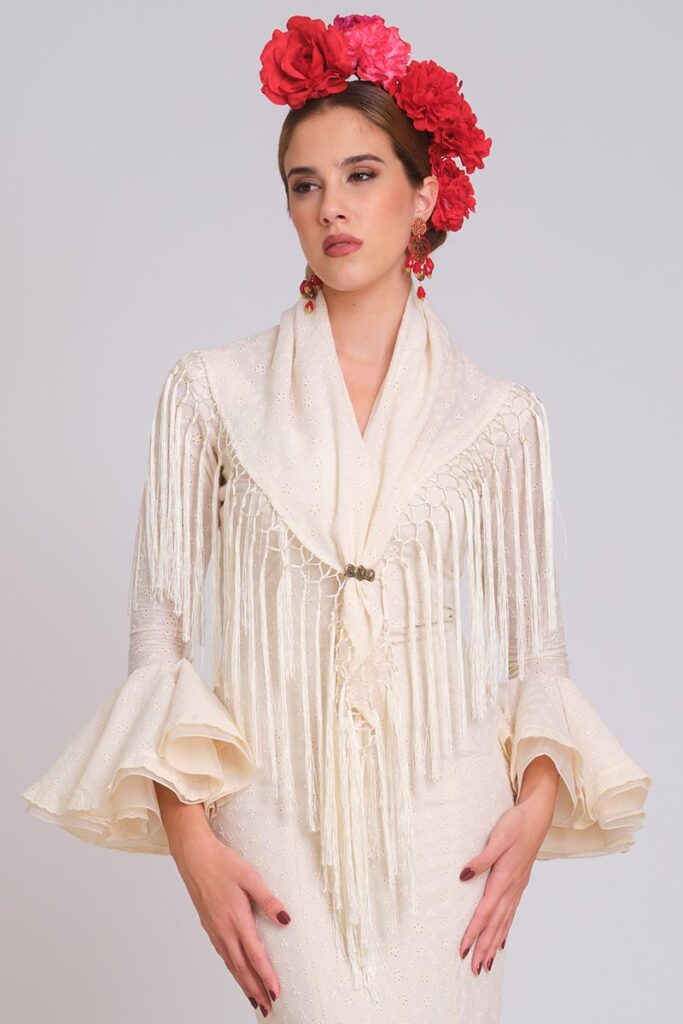 Traje de flamenca marfil con mantoncillo a juego, flecos y mangas de volantes para feria sofisticada