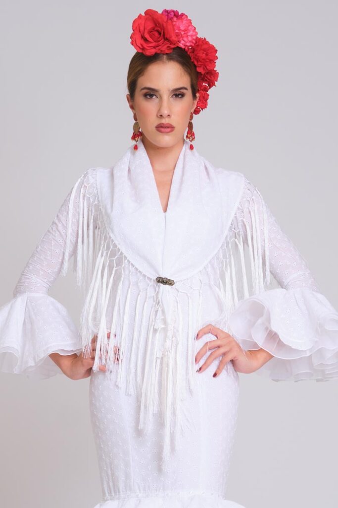 Traje de flamenca blanco con mantoncillo a juego, flecos y mangas de volantes para feria elegante