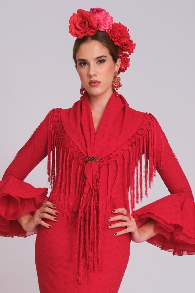 Traje de flamenca rojo con mantoncillo liso a juego, flecos y mangas con volantes para feria