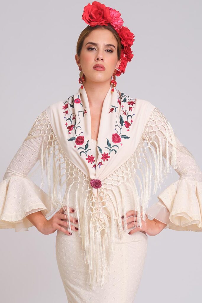 Mantoncillo beige bordado con flores rojas sobre traje de flamenca blanco con volantes