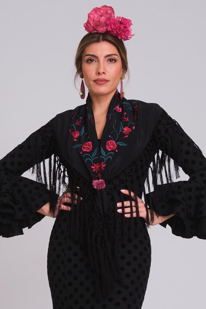 Vestido de flamenca negro con mantoncillo bordado y flores rosas para feria elegante