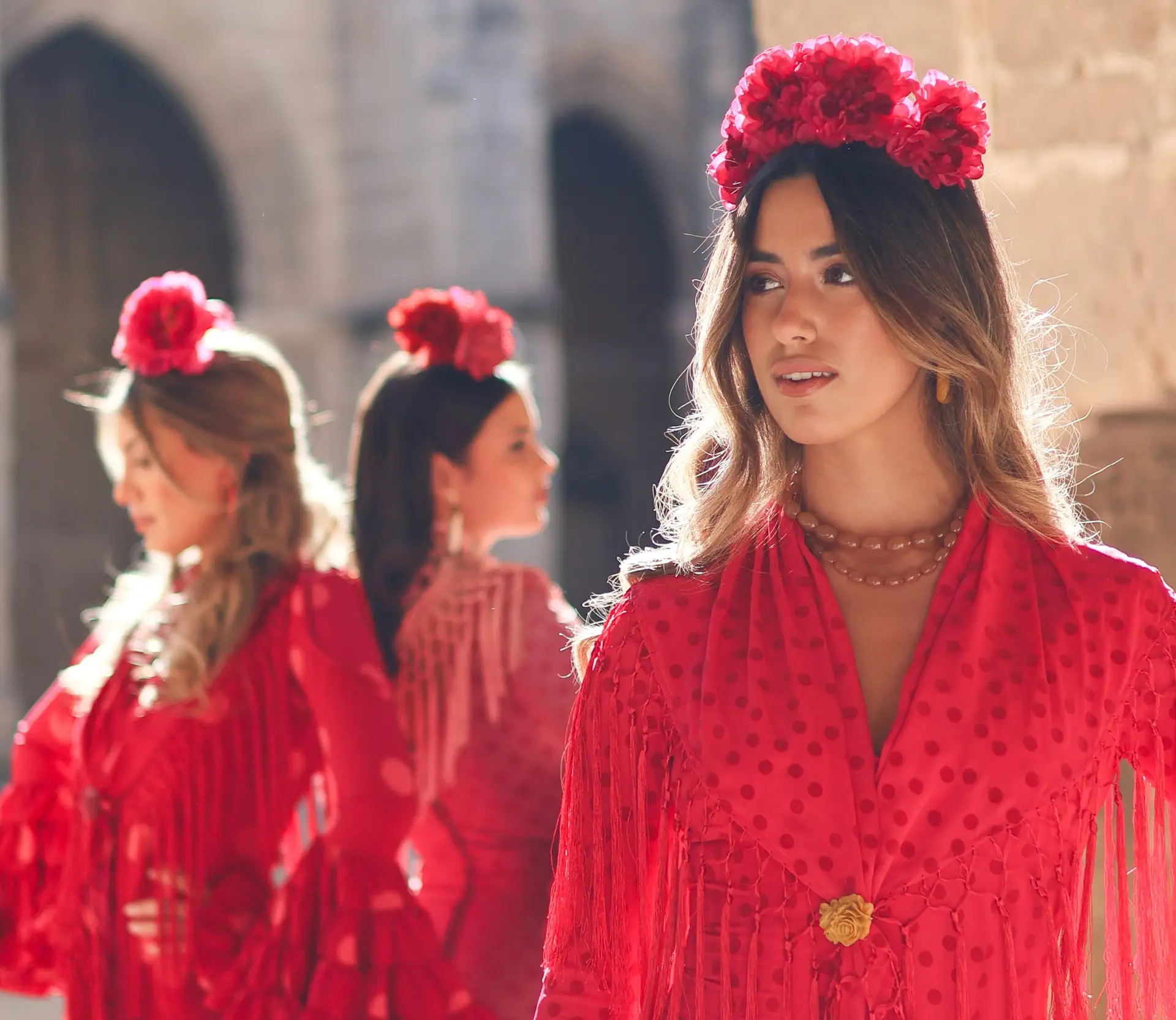 Tres mujeres con trajes de flamenca rojos y flores en el cabello